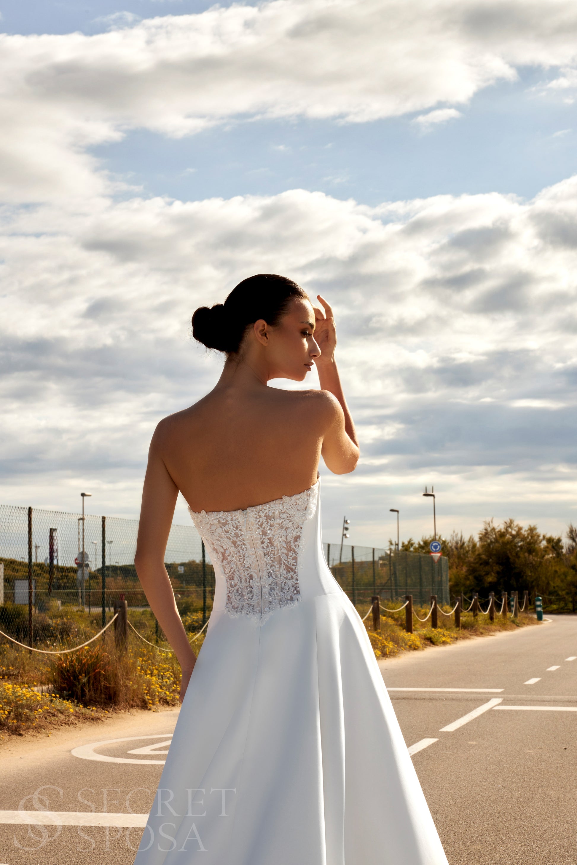 Bride in classic A-line atlas wedding gown with lace detail, V-cut neckline, drop waist, straight zip-closure back, and chapel train.