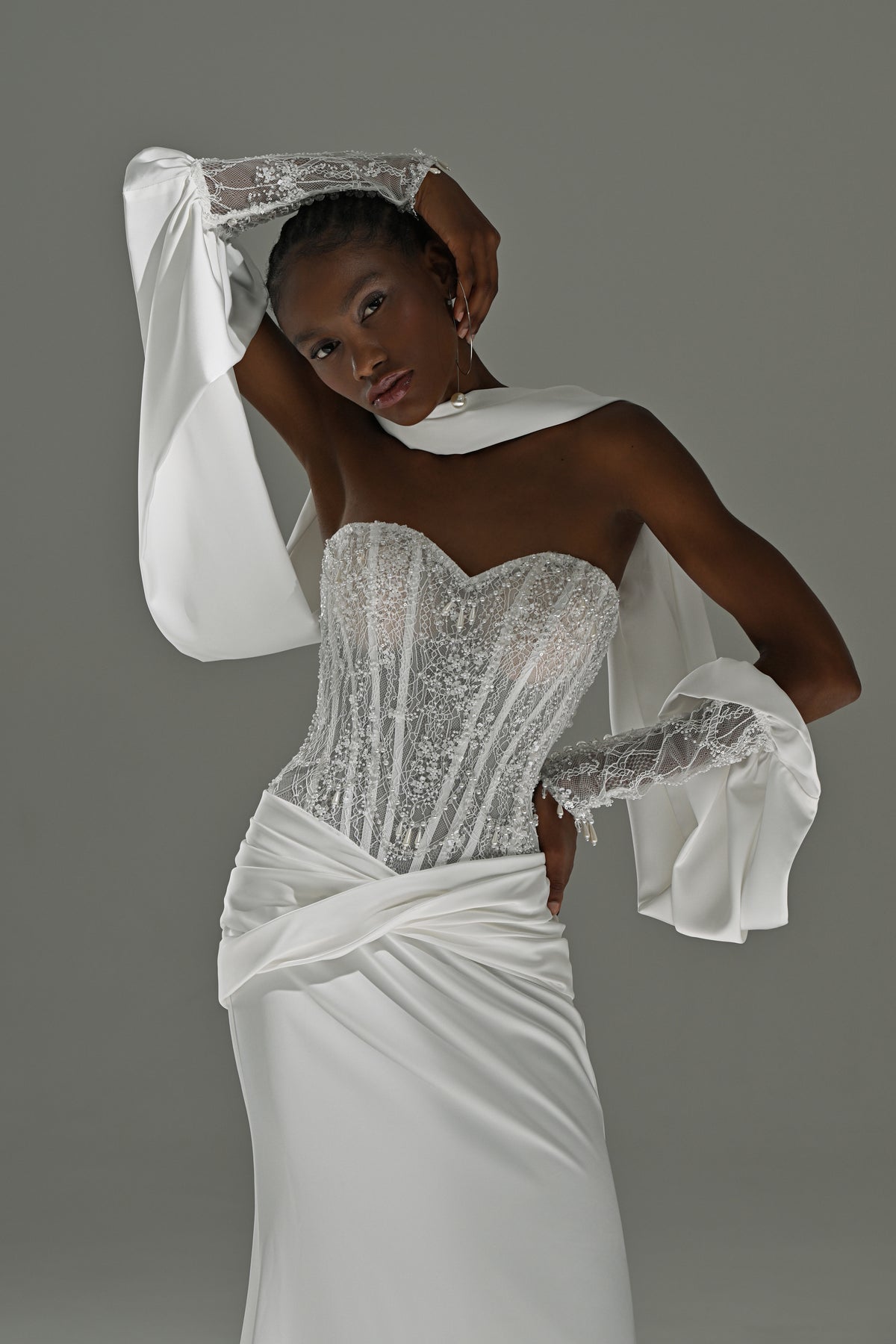 Satin sheath wedding dress with lace corset – close-up of the corset, draped hip and single oversized sleeve