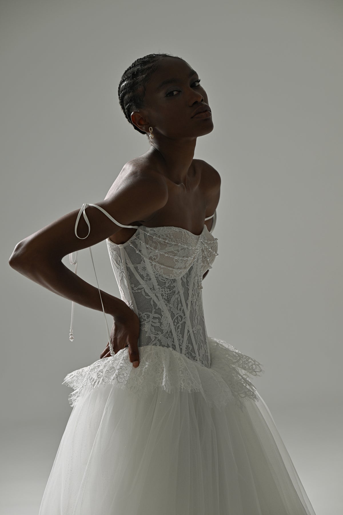 Lace and tulle ball gown wedding dress with corset bodice – close-up of the beaded corset and peplum, hand on hip