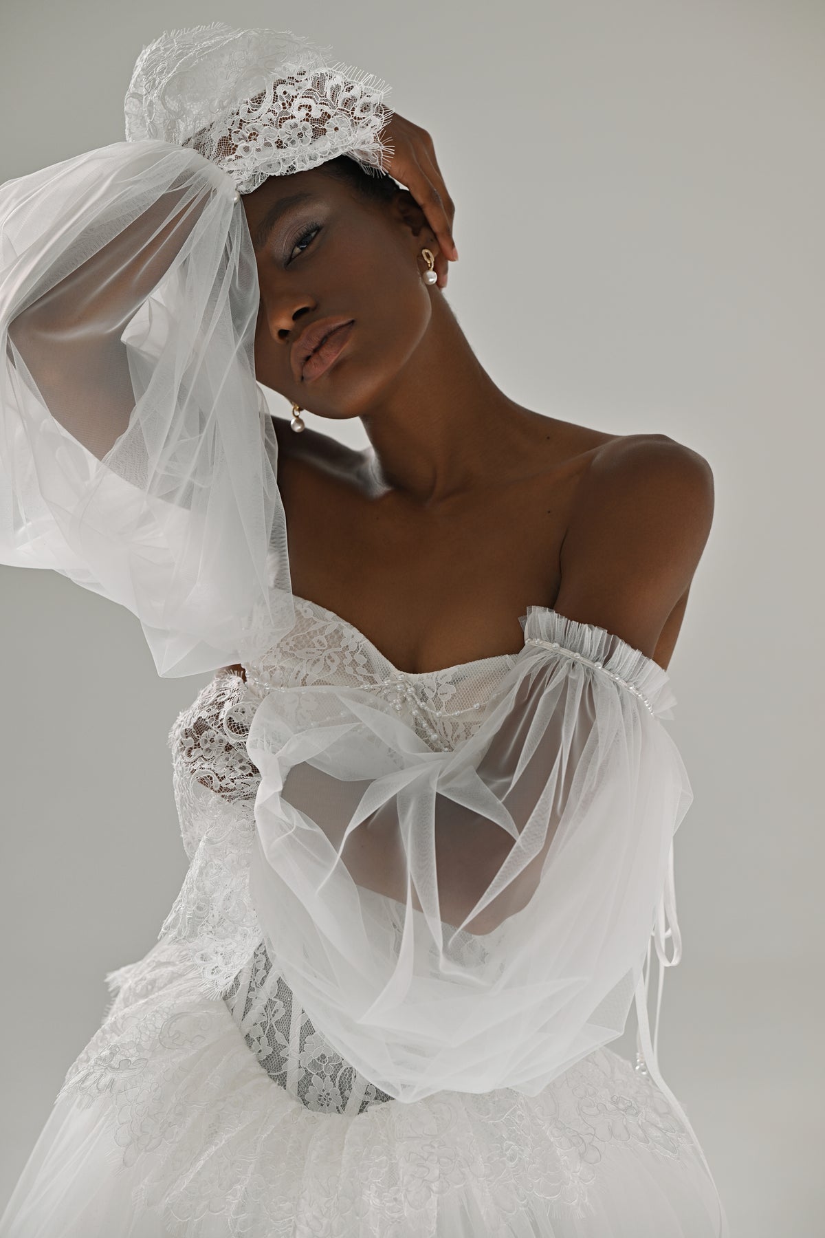 Lace and tulle ball gown wedding dress – close-up of the corset with sheer sleeve raised to the head