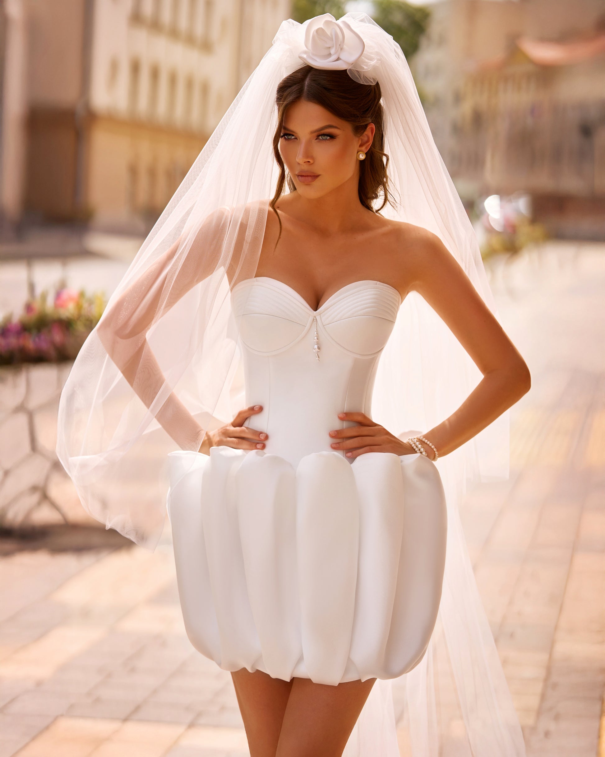 Bride in strapless Mikado mini wedding dress with corset-style bodice and bubble-hem skirt, ideal for reception or city celebration.