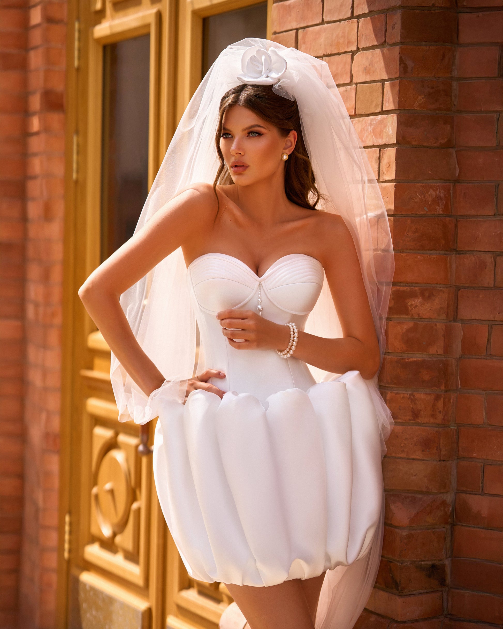 Bride in strapless Mikado mini wedding dress with corset-style bodice and bubble-hem skirt, ideal for reception or city celebration.