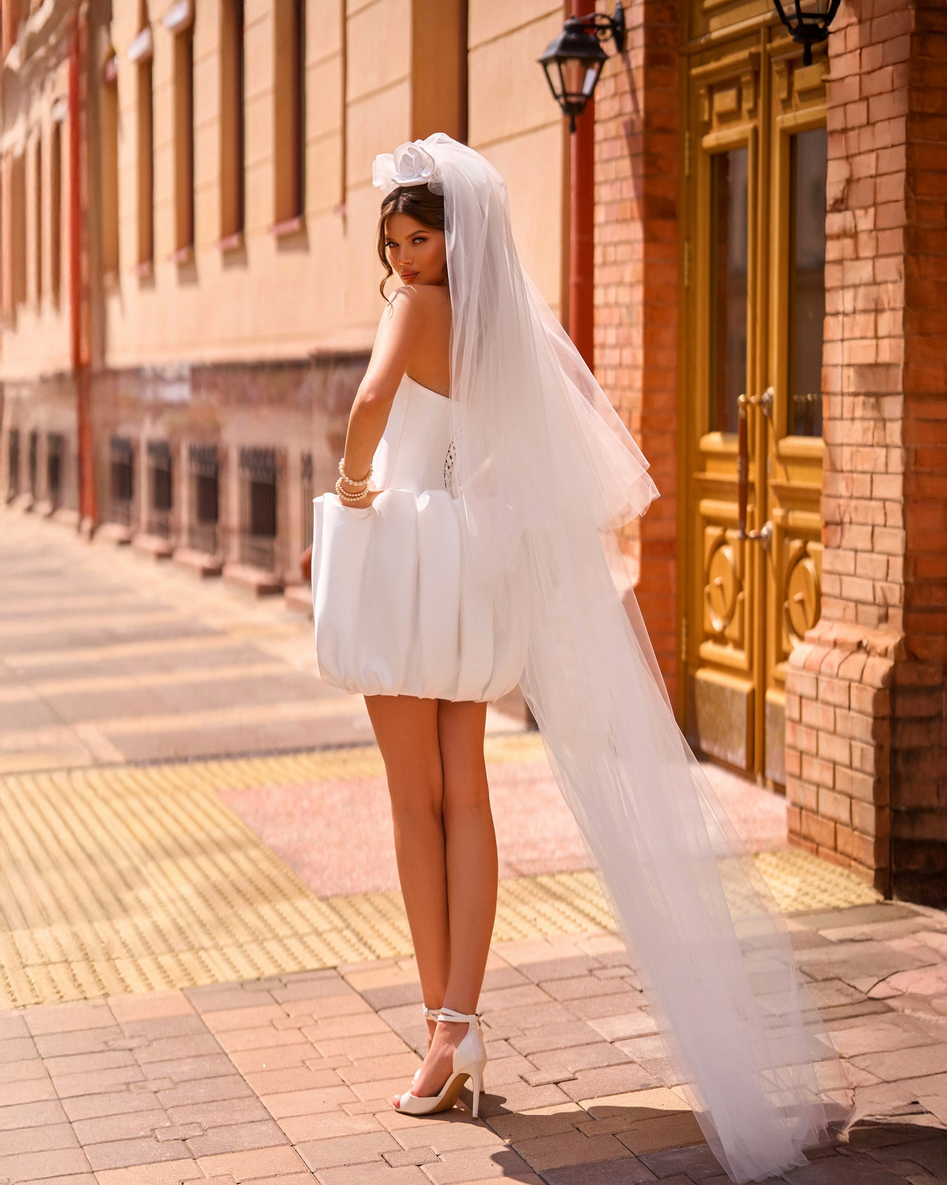 Bride in strapless Mikado mini wedding dress with corset-style bodice and bubble-hem skirt, ideal for reception or city celebration.