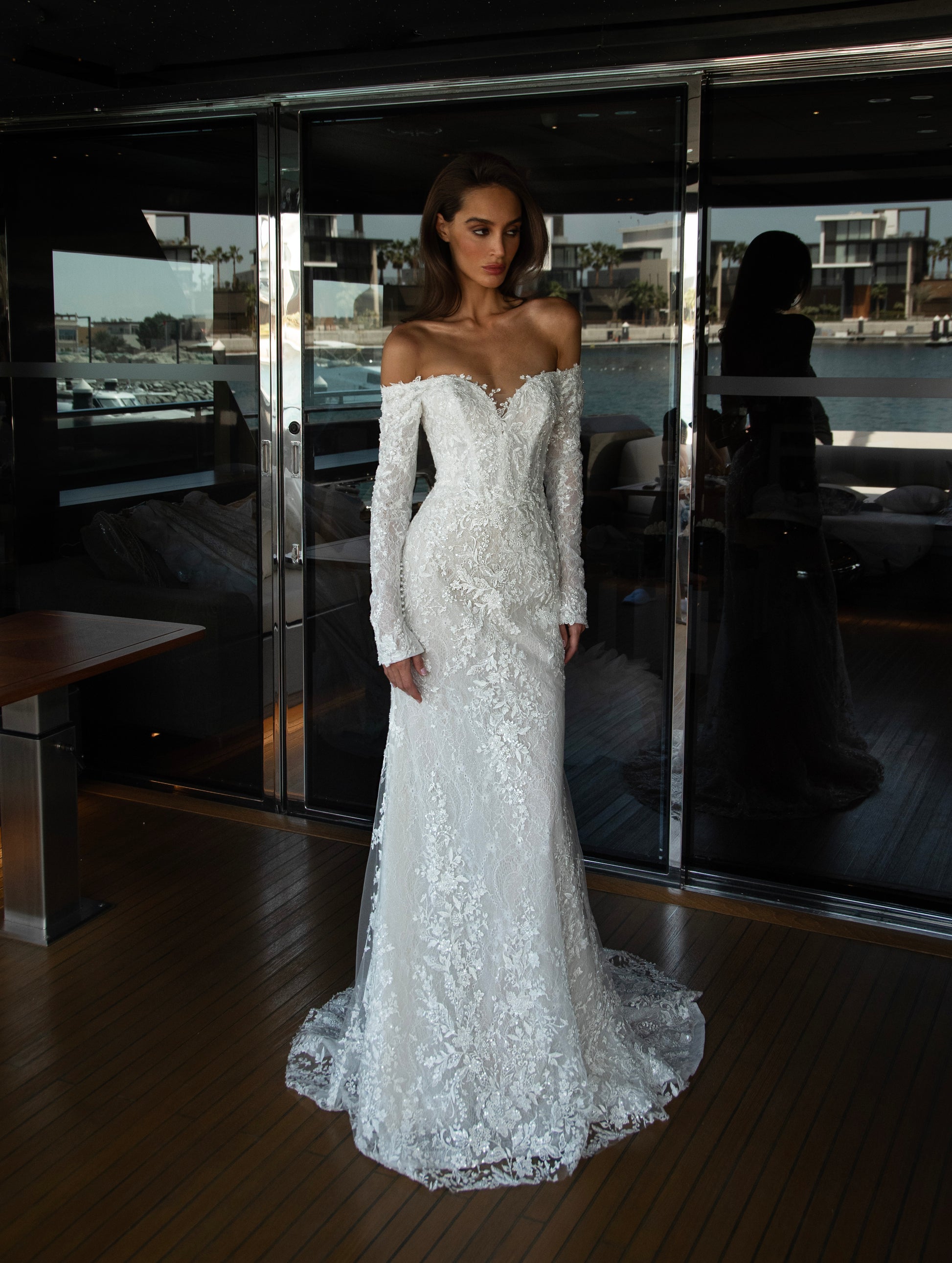 Camber off-shoulder lace wedding gown with detachable tulle overskirt. A romantic mermaid silhouette with illusion sleeves, hand-applied lace, and a sculpted corset bodice for two stunning bridal looks in one.