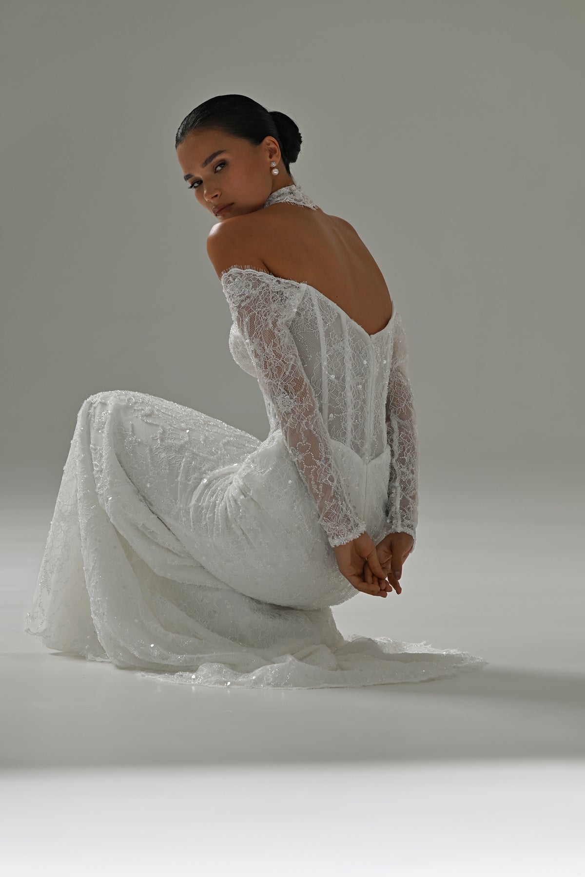 Lace mermaid wedding dress with off-shoulder long sleeves – seated side view of the open back and train