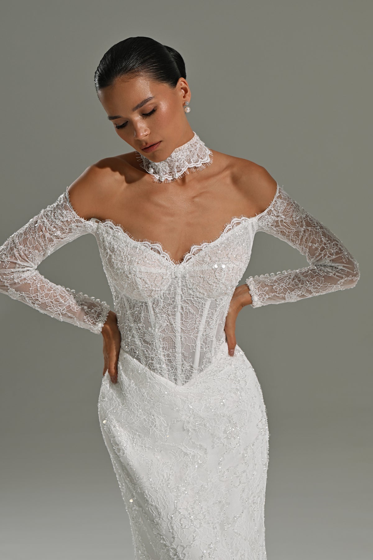 Lace mermaid wedding dress with sweetheart corset and lace sleeves – close-up of the corset bodice, hands on hips