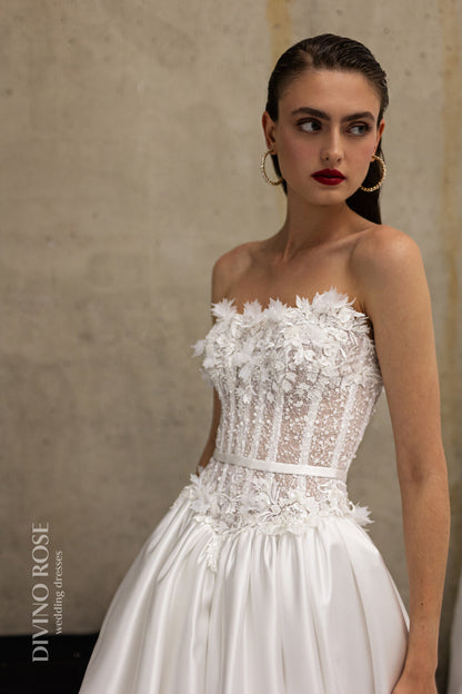 Sleeveless wedding dress with lace corset and floral details.