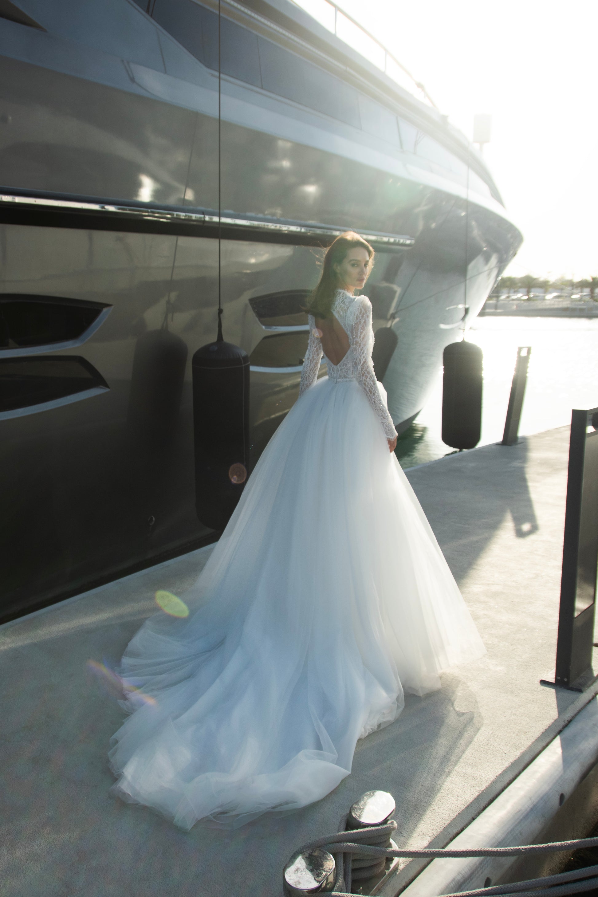 Celeste beaded lace long-sleeve sheath wedding dress with high neck and detachable tulle overskirt, open-back detail.