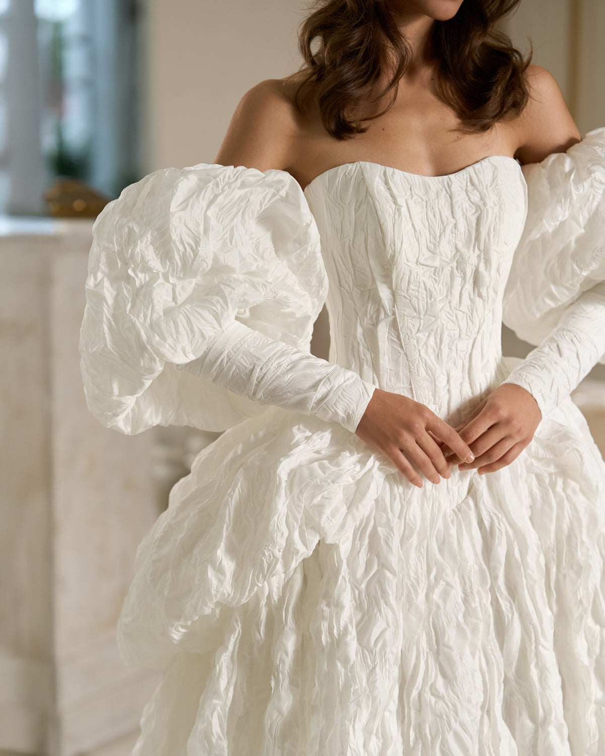 Front detail of a white textured taffeta wedding dress with a basque waist and voluminous puff sleeves.