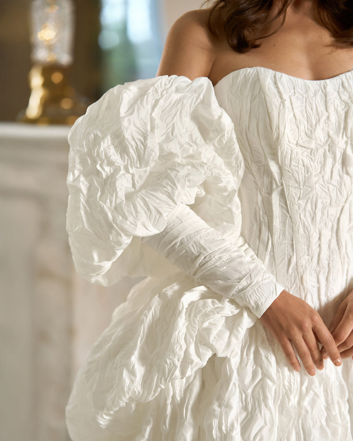 Close-up of the puff sleeve, fitted cuff and draped hip detailing on a white textured taffeta wedding dress.