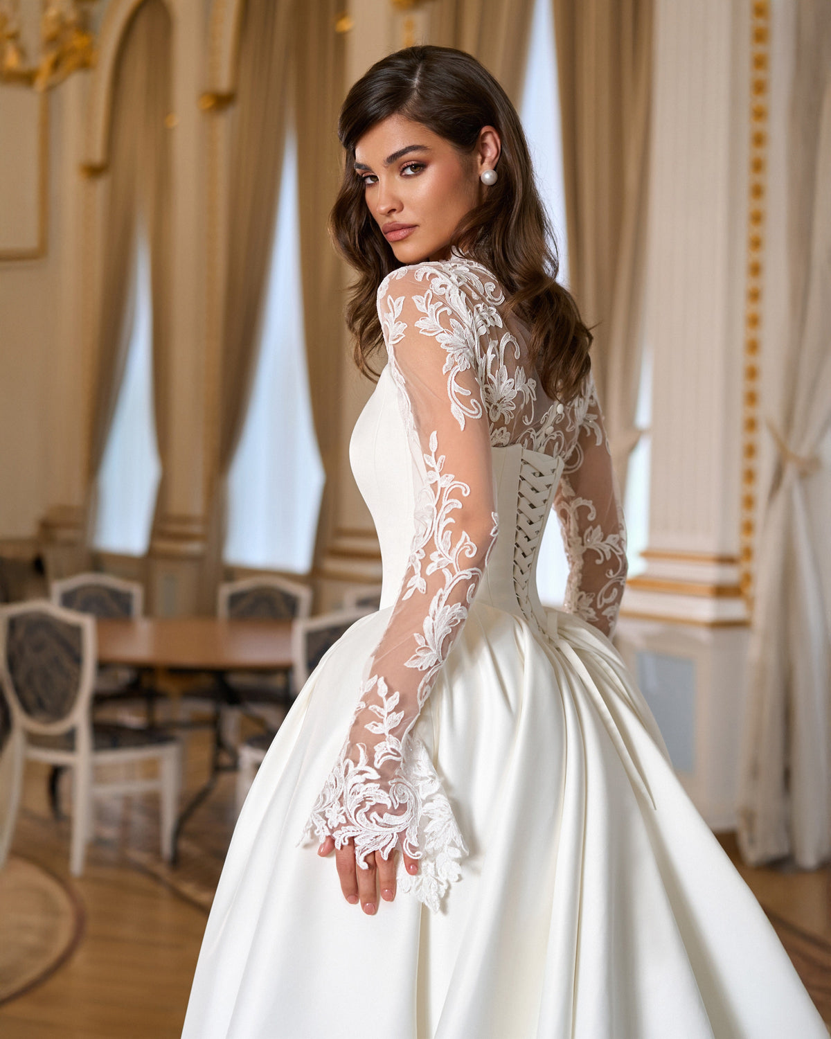 Three-quarter rear view of the fitted basque waist bodice, sheer floral lace back and long lace sleeve.