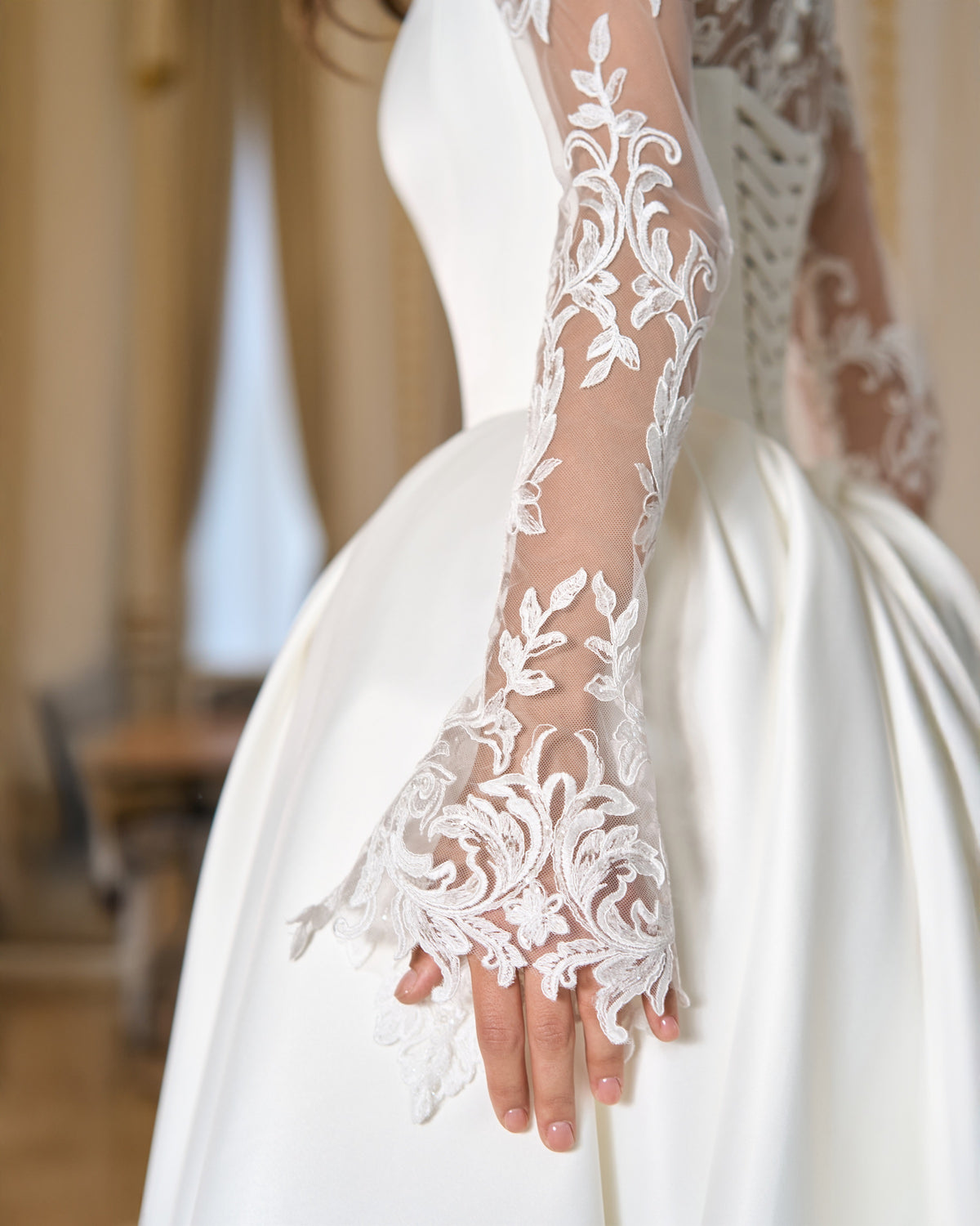Close-up of the long sheer floral lace sleeve and intricate lace cuff beside the gathered skirt.