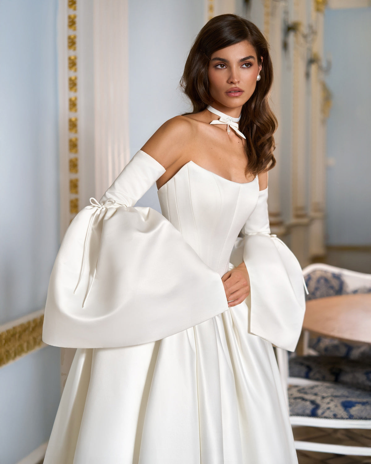 Three-quarter close-up of the ivory corset-style bodice, detachable bell sleeves and matching bow choker.