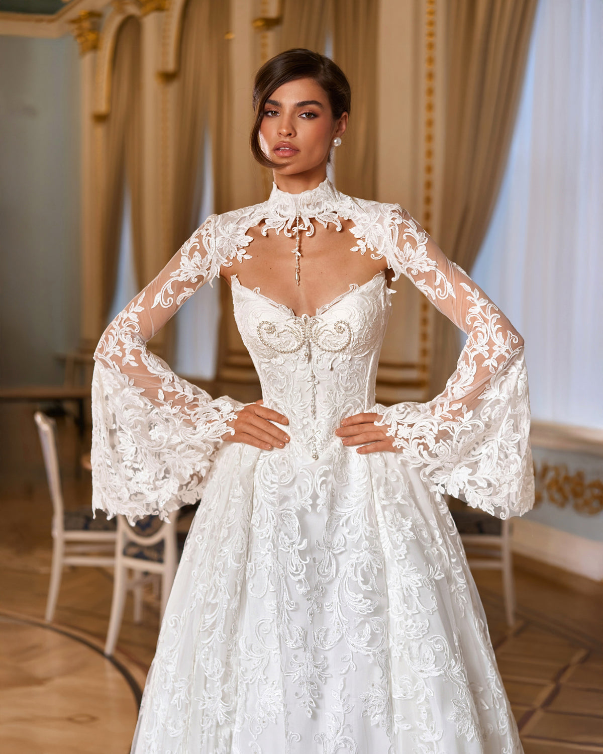 A-line lace wedding dress with pearl corset bodice and lace bolero, hands on hips