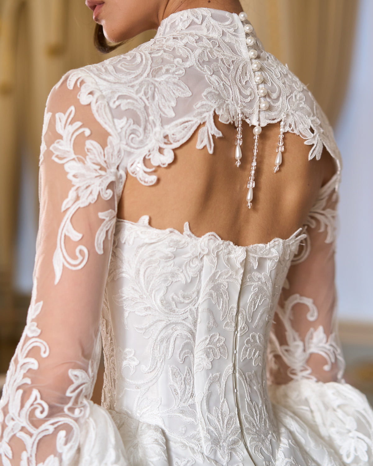 Back view of lace bolero with pearl buttons, keyhole opening and pearl fringe over a corset back