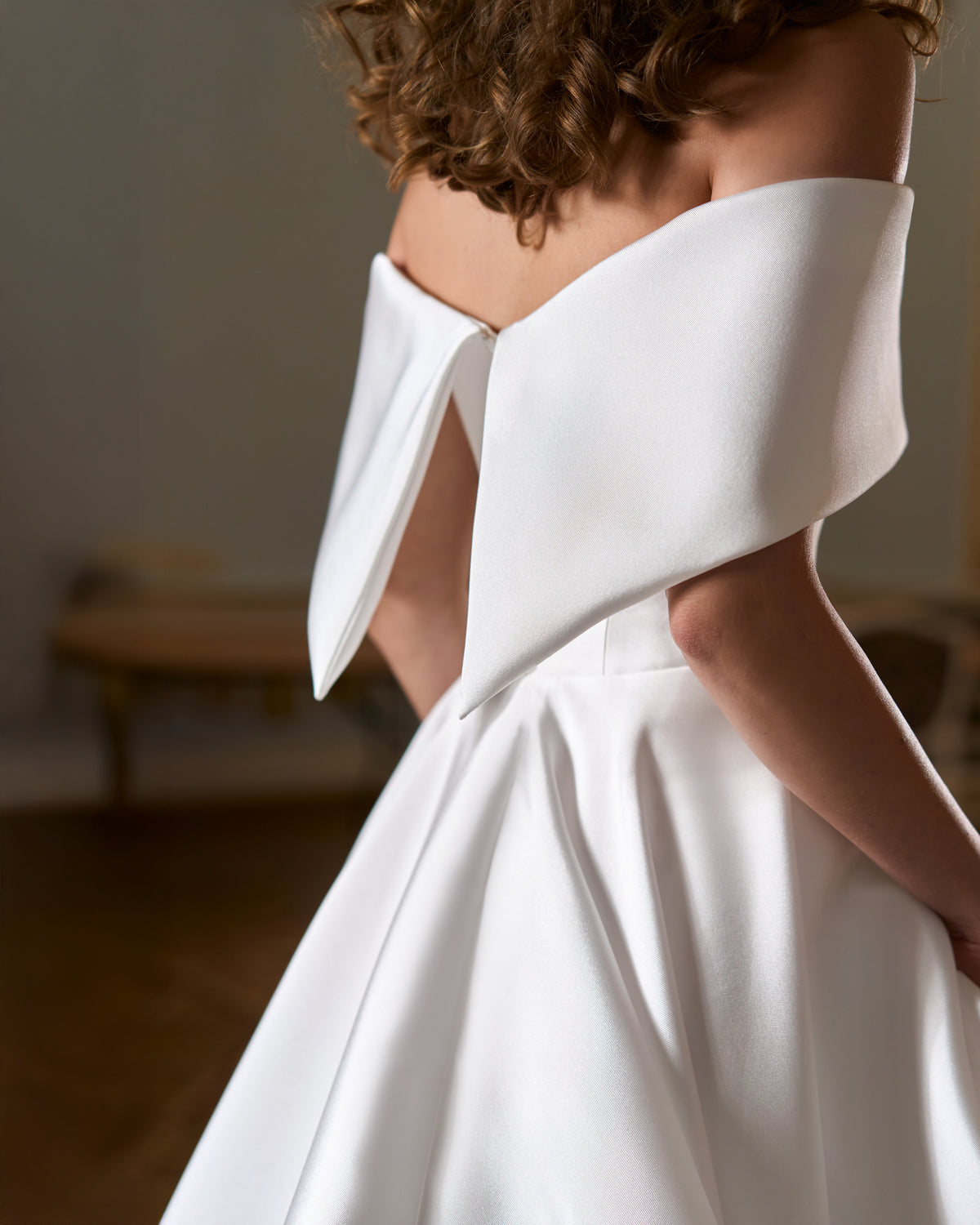 Close view of folded off-the-shoulder cuff with pointed ends over a smooth A-line skirt