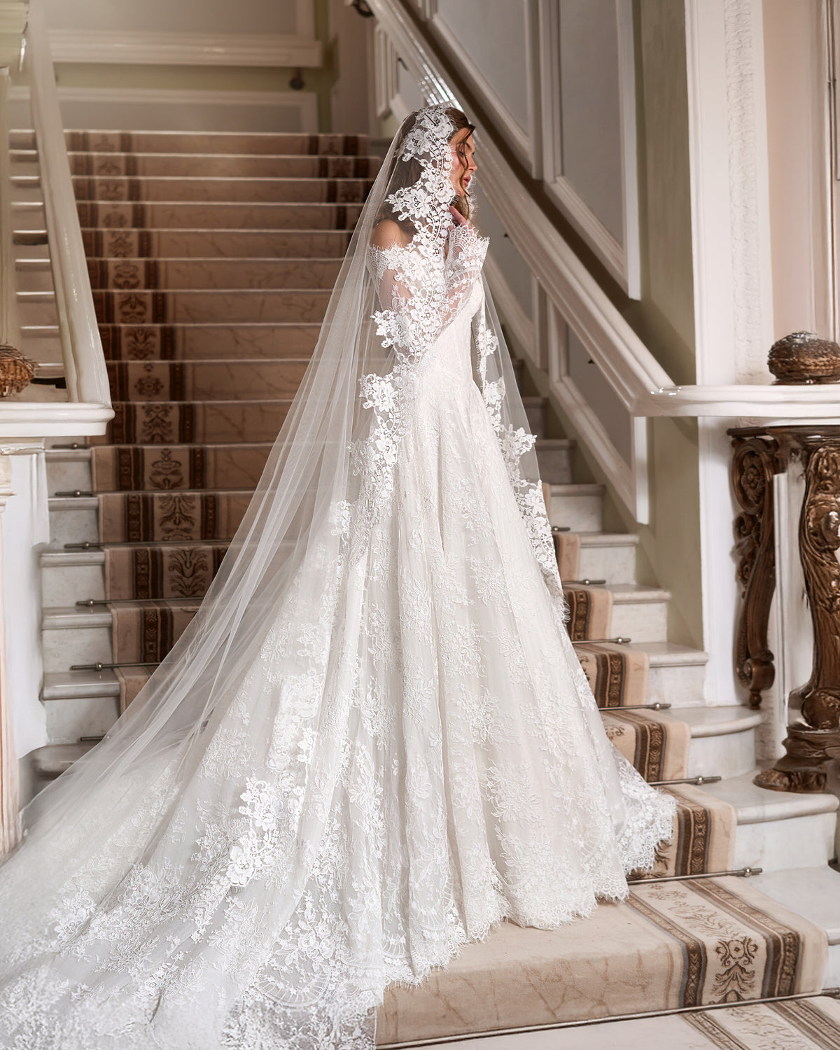 A-line lace wedding dress with sheer long sleeves, a full skirt and a long tulle veil edged with floral lace appliques.