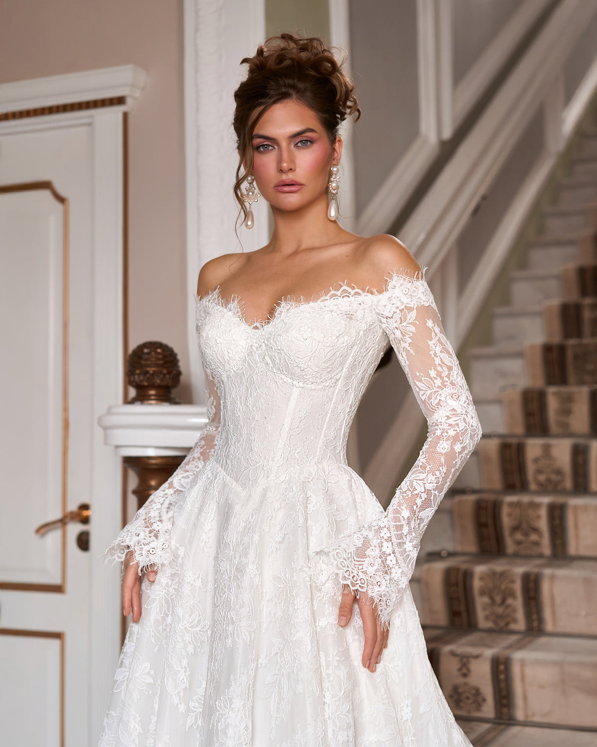 A-line lace wedding dress with a pointed corset waist, sweetheart neckline and long sleeves with scalloped cuffs.