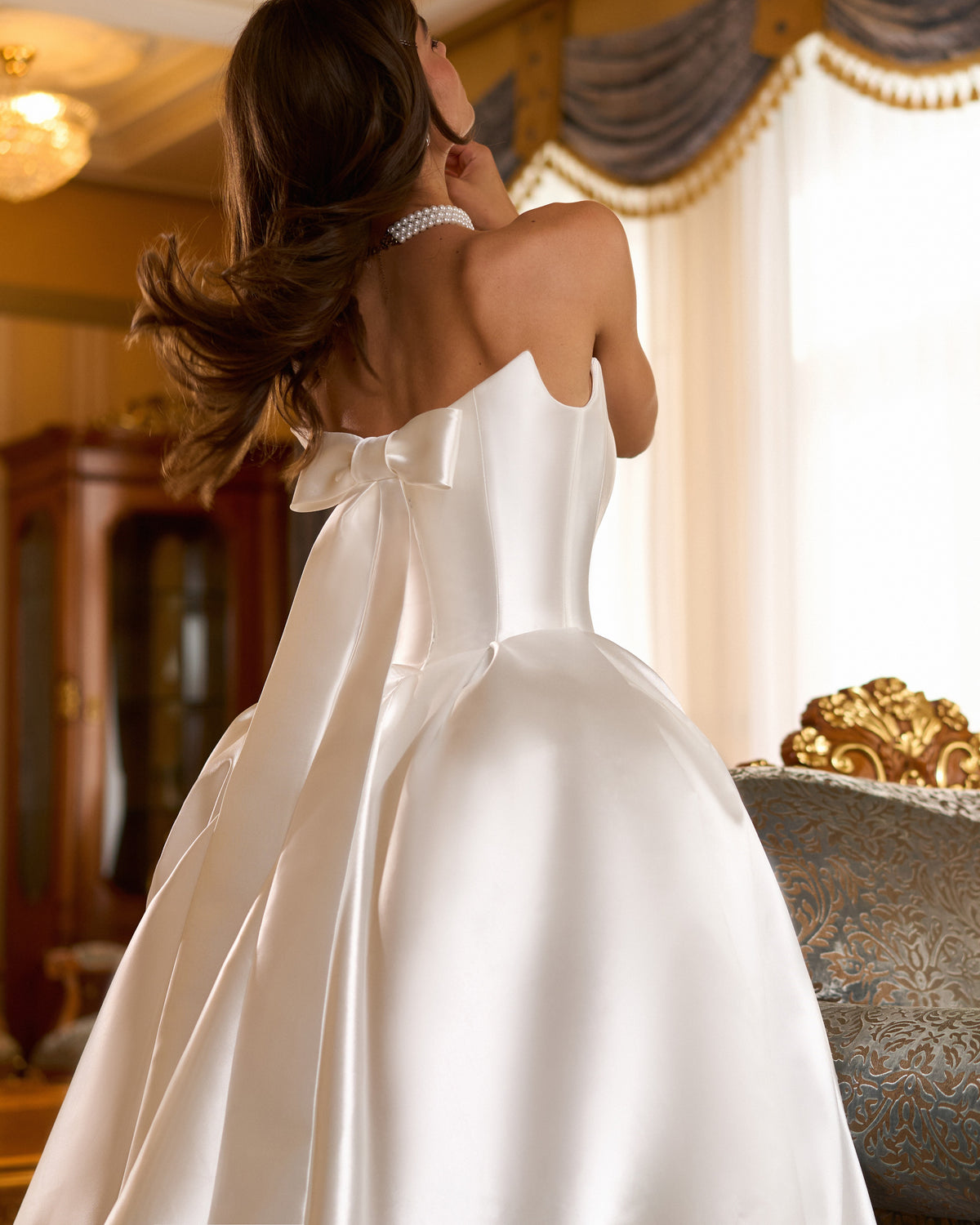 Back view of strapless satin ball gown with large bow at the corset back and full skirt