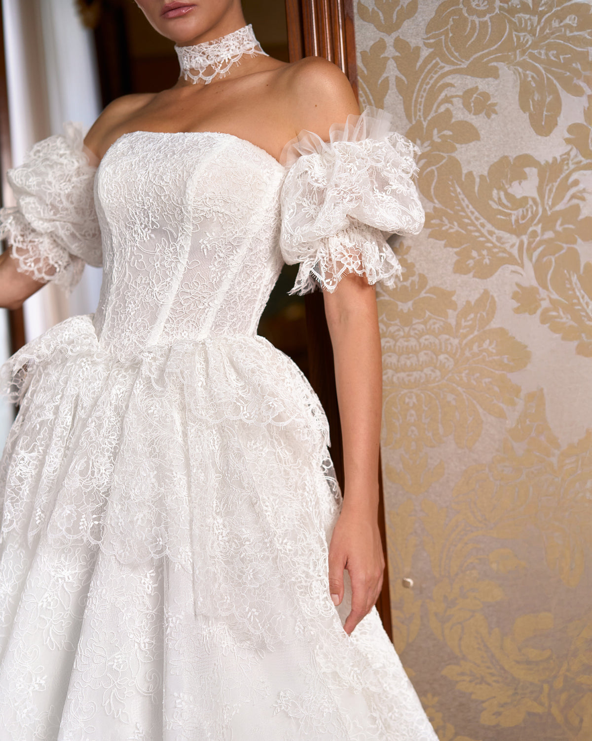 Side view of strapless lace corset bodice, tiered peplum and off-the-shoulder lace puff sleeve