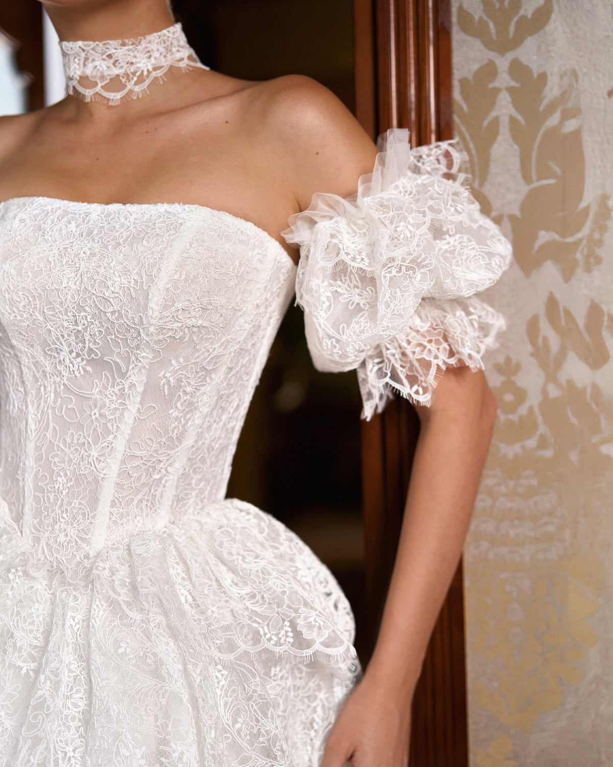 Close view of lace puff sleeve with tulle ruffle, lace choker and strapless corset bodice