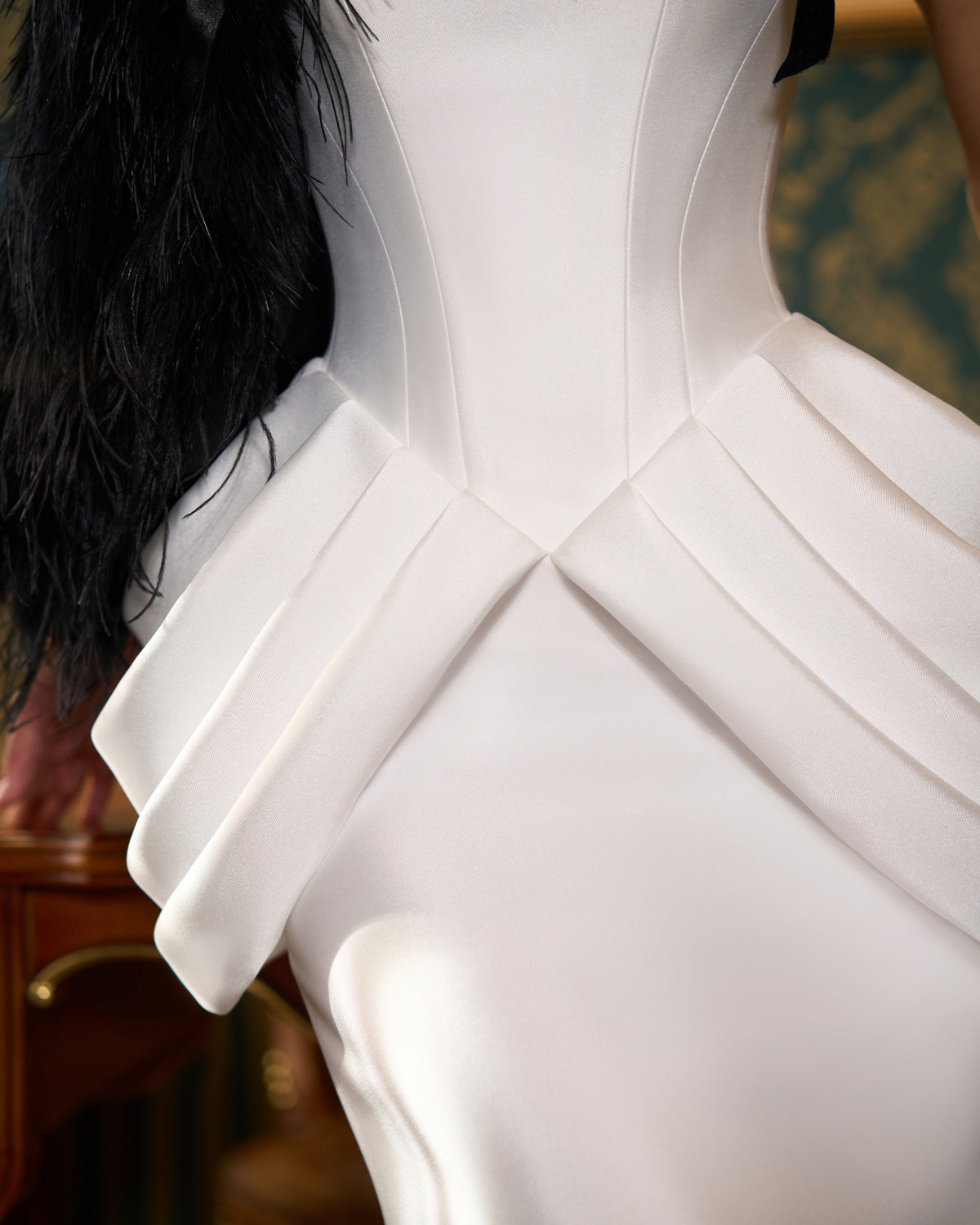 Detail of the corset-style waist and symmetrical folded hip panels on the fit-and-flare wedding dress.