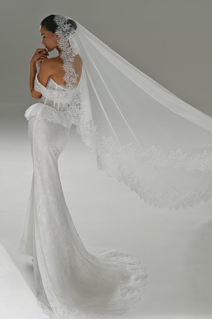 Lace mermaid wedding dress with off-shoulder corset – three-quarter view with the long lace-trimmed veil flowing