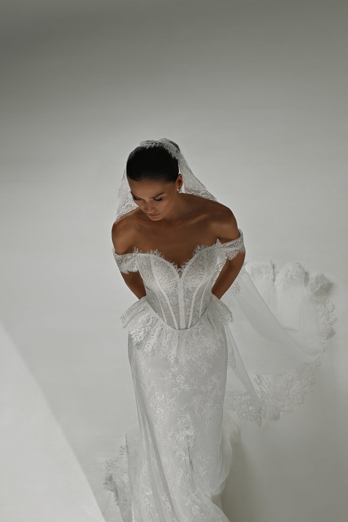 Lace mermaid wedding dress with off-shoulder sweetheart corset – high-angle view with the veil flowing