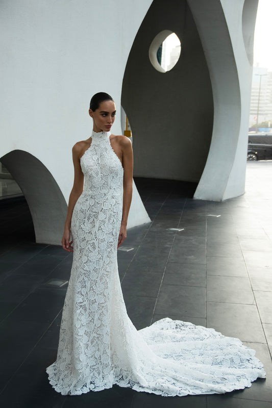 Backless halter lace sheath wedding dress with detachable tulle overskirt and cathedral train, photographed in the city.