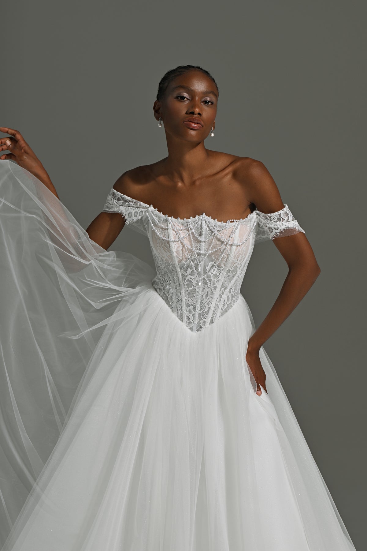 Tulle ball gown wedding dress with off-shoulder lace corset – close-up of the beaded corset and full skirt, hand on hip
