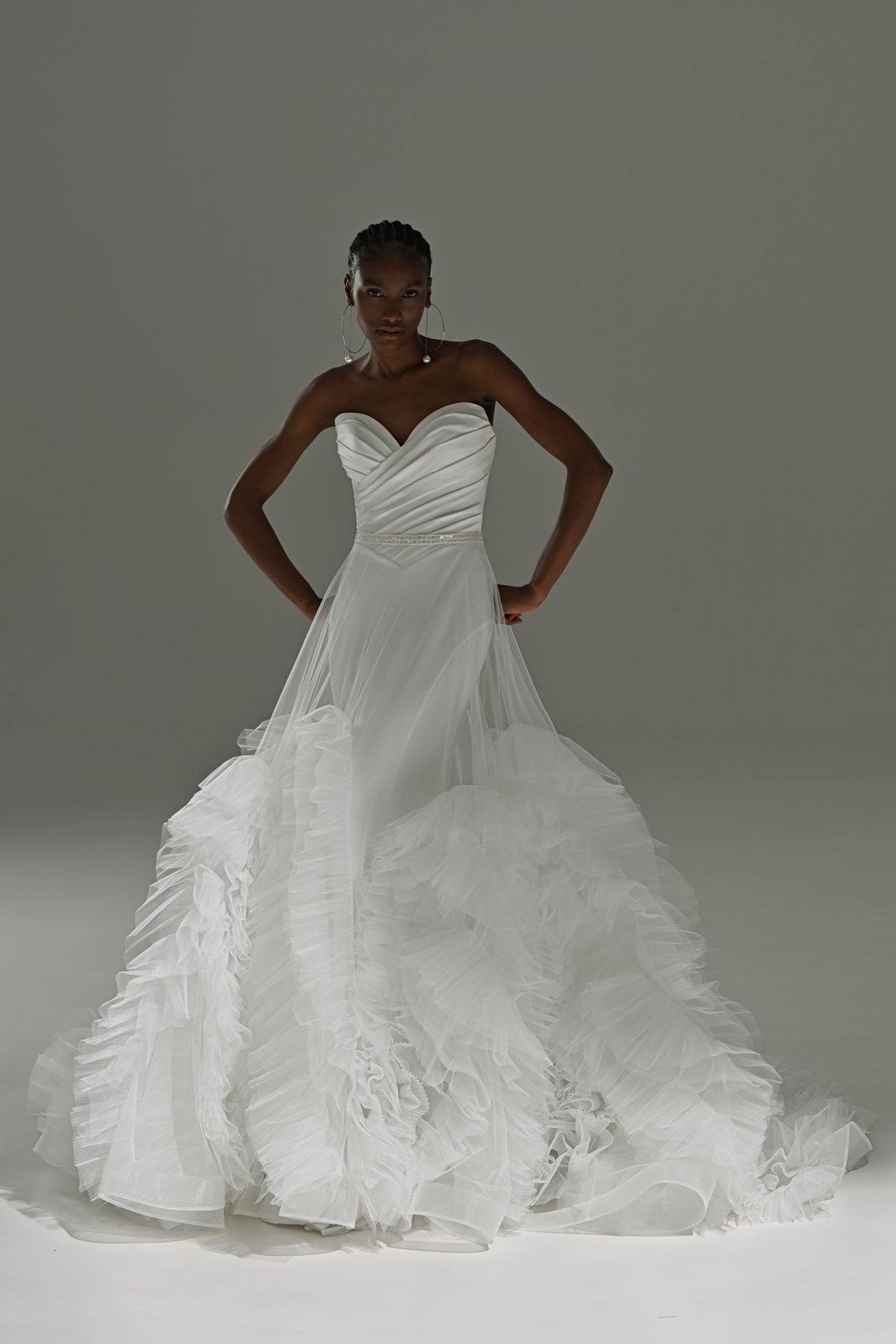 Stretch satin mermaid wedding dress with ruched sweetheart bodice – front view with the ruffled tulle skirt, hands on hips