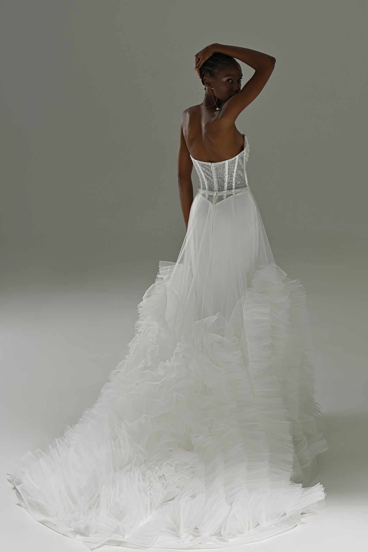 Stretch satin mermaid wedding dress with tulle skirt – back view with the corset back and ruffles, arm raised
