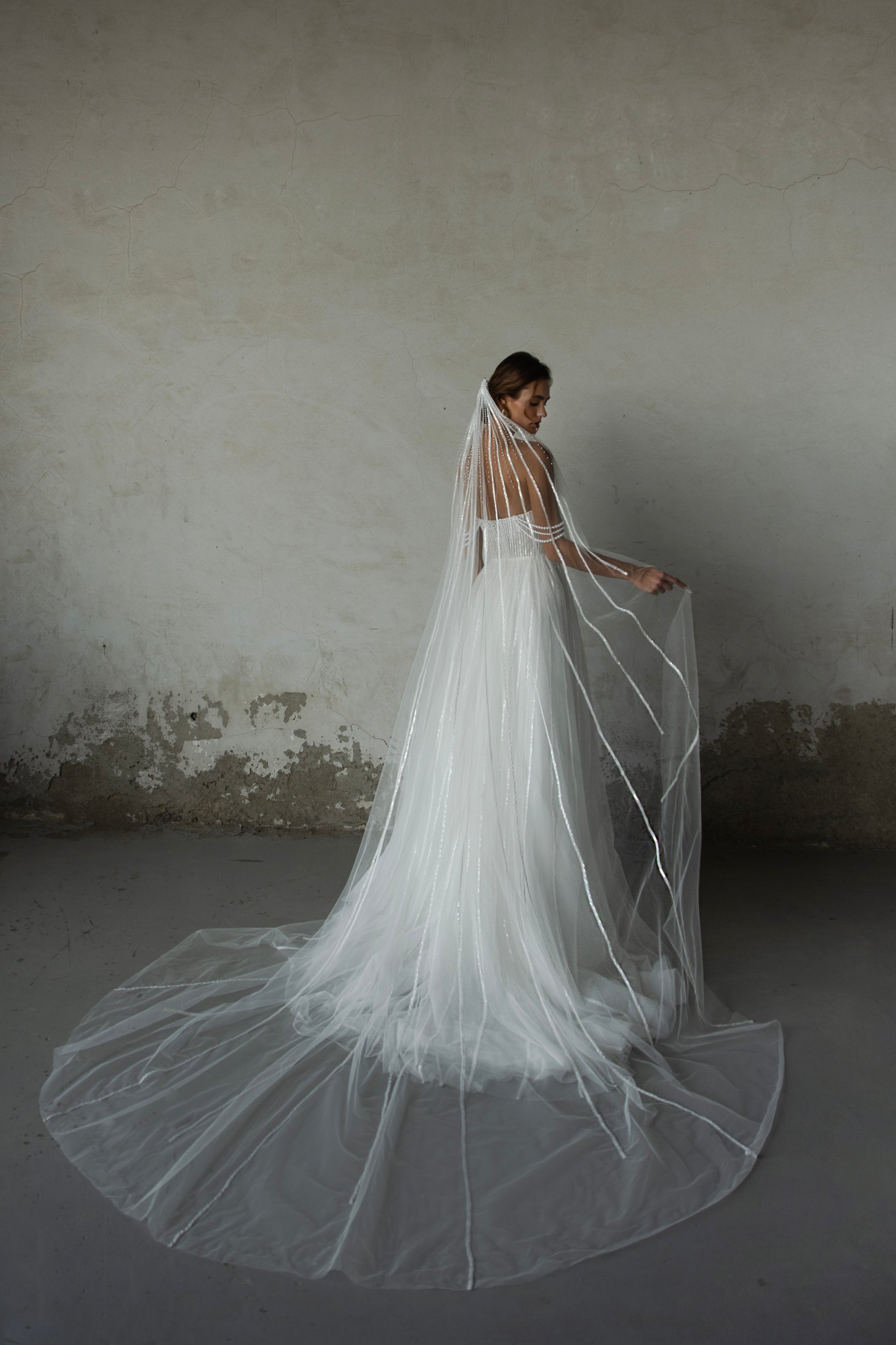 Pearl-embroidered tulle wedding dress with beaded corset bodice, detachable sheer sleeves, thigh-high slit, and flowing layered skirt