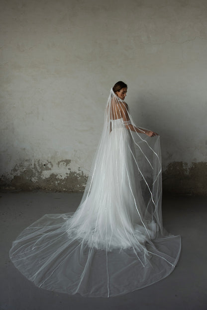 Pearl-embroidered tulle wedding dress with beaded corset bodice, detachable sheer sleeves, thigh-high slit, and flowing layered skirt