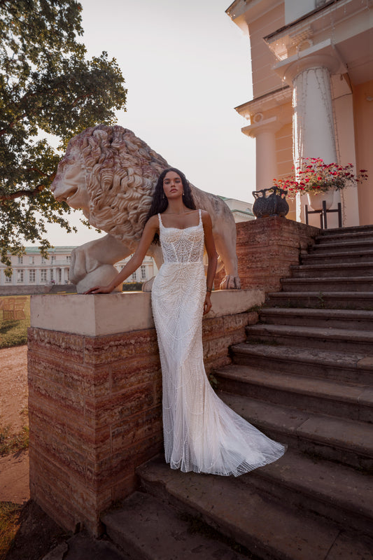 Beaded mermaid wedding gown with geometric pearl embroidery, sheer corset bodice, and elegant train.