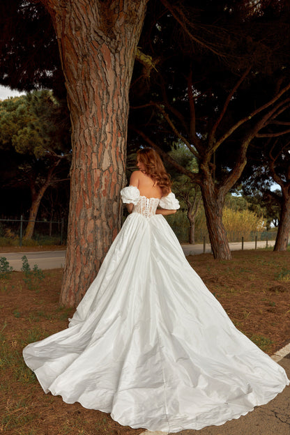 Bride in princess A-line wedding gown with puffy off-shoulder sleeves, lace bodice, lace-up waist, plain taffeta skirt, and cathedral train.