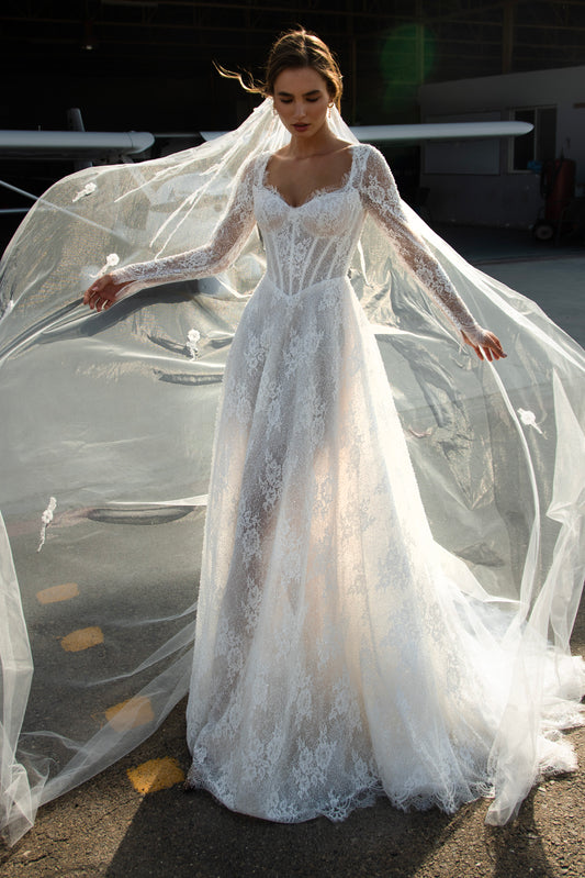 Sequin lace A-line wedding dress featuring long sheer sleeves, illusion scoop back with button-up closure, drop-down waist, and flowing court train