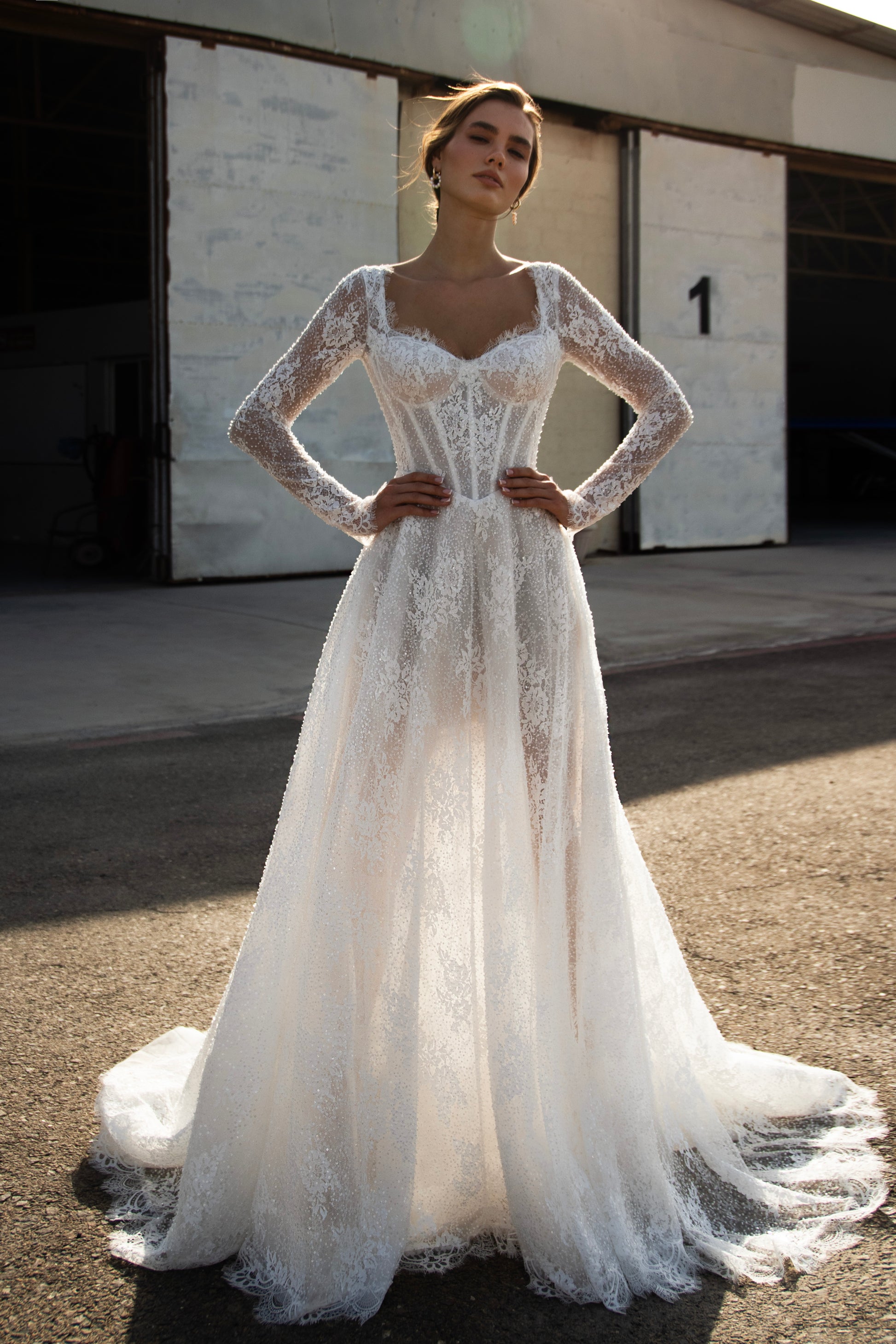 Sequin lace A-line wedding dress featuring long sheer sleeves, illusion scoop back with button-up closure, drop-down waist, and flowing court train