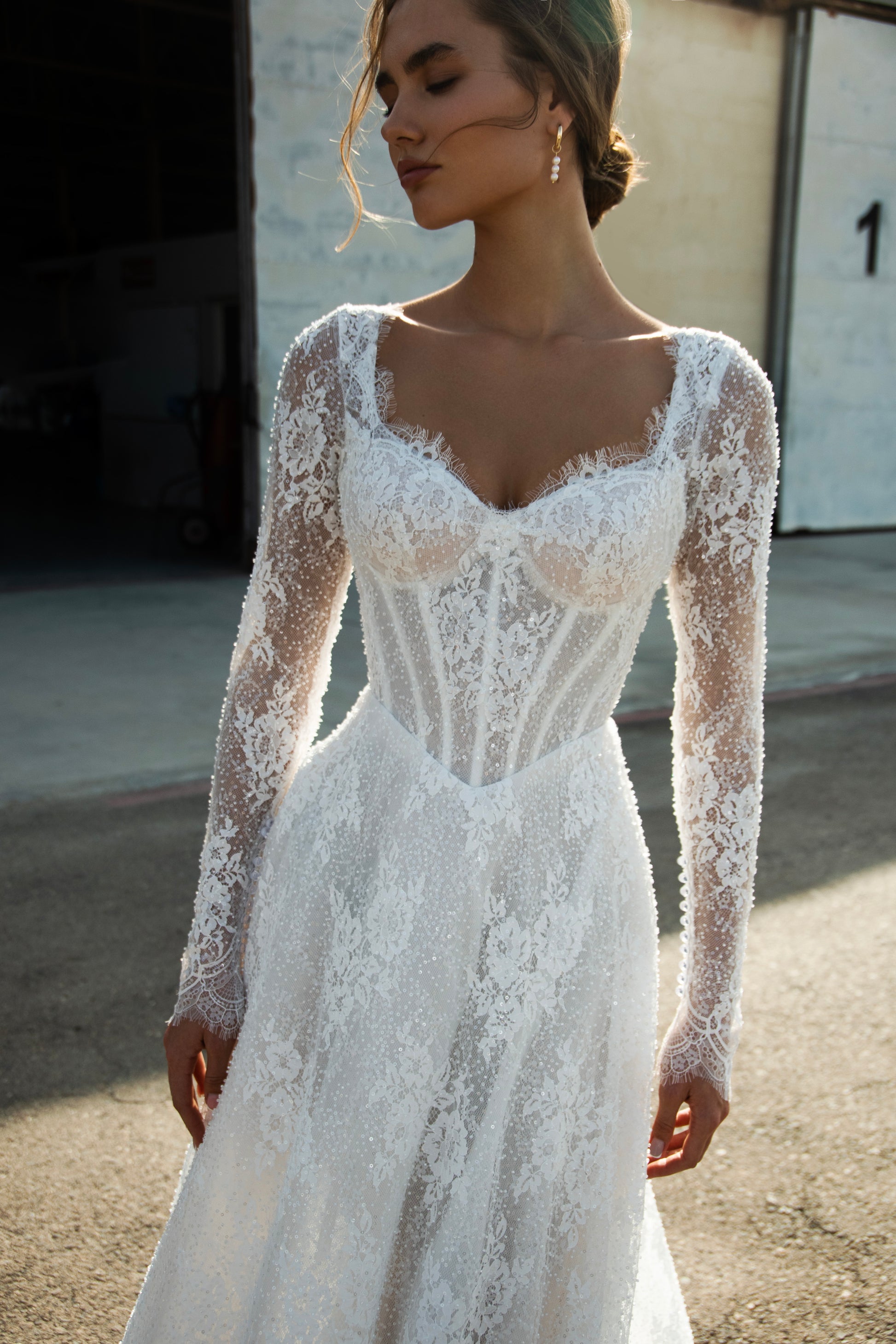 Sequin lace A-line wedding dress featuring long sheer sleeves, illusion scoop back with button-up closure, drop-down waist, and flowing court train