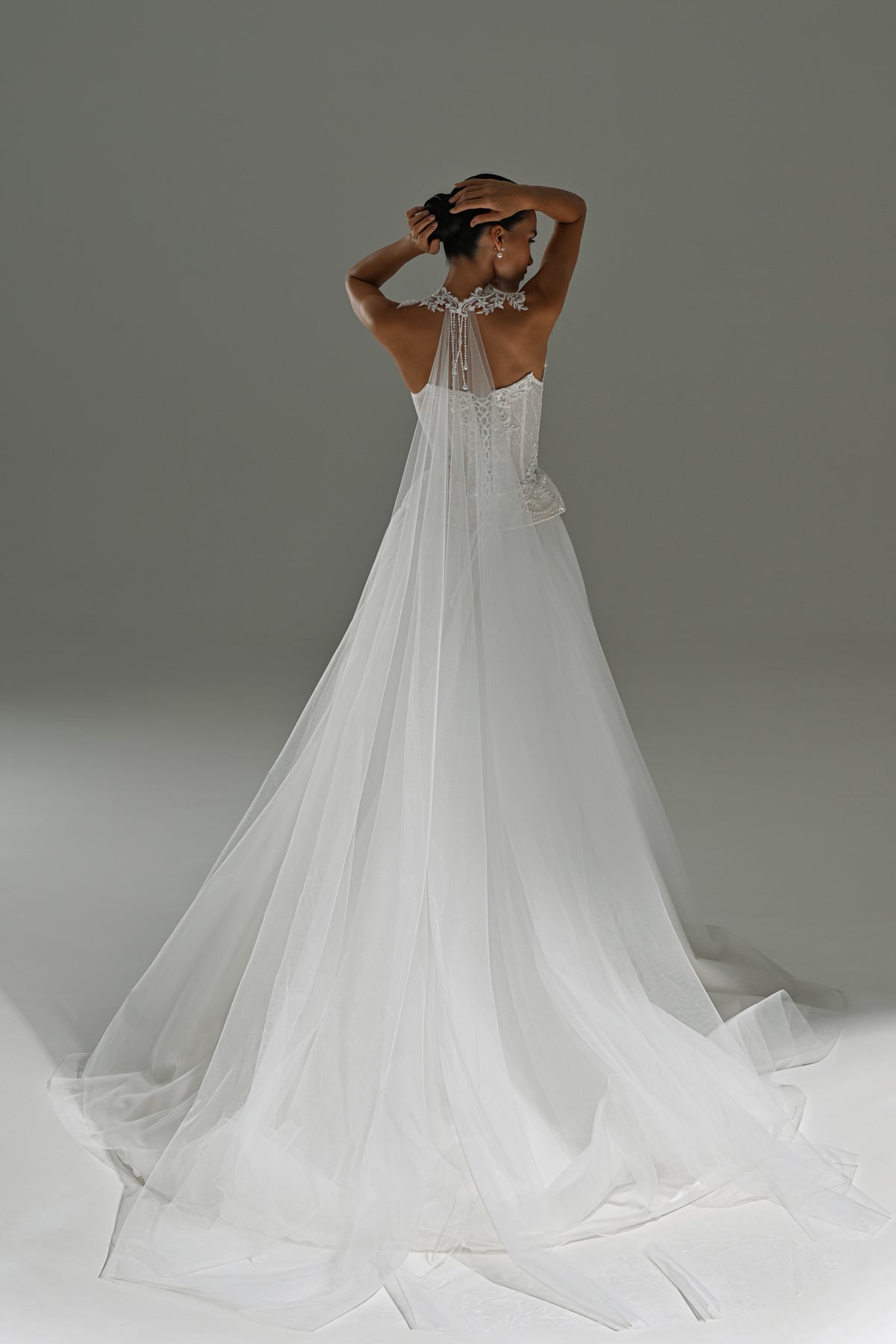 Lace corset wedding dress with removable tulle skirt – back view with arms raised and the long train