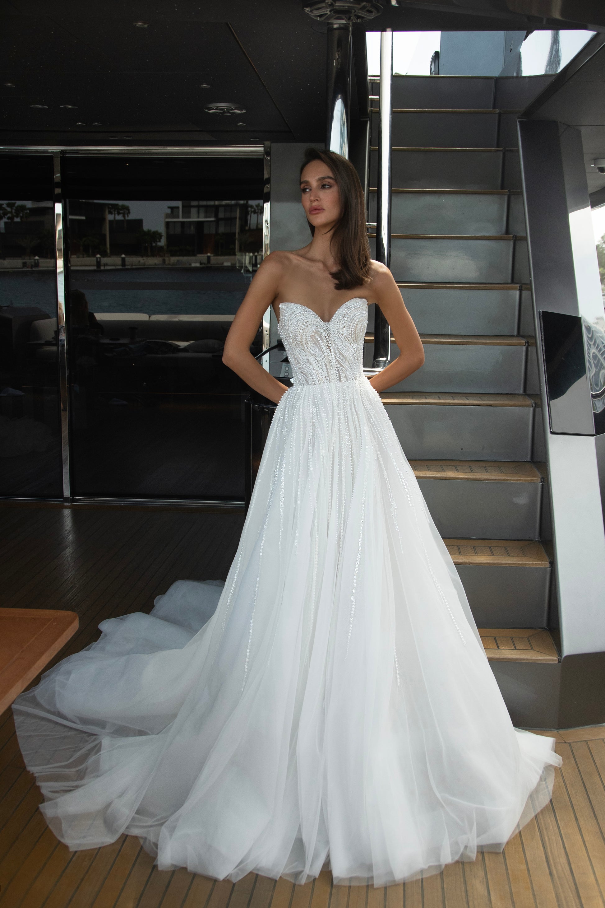 Bride wearing a beaded A-line wedding gown with sweetheart neckline and detachable illusion bolero featuring long sleeves and open back.