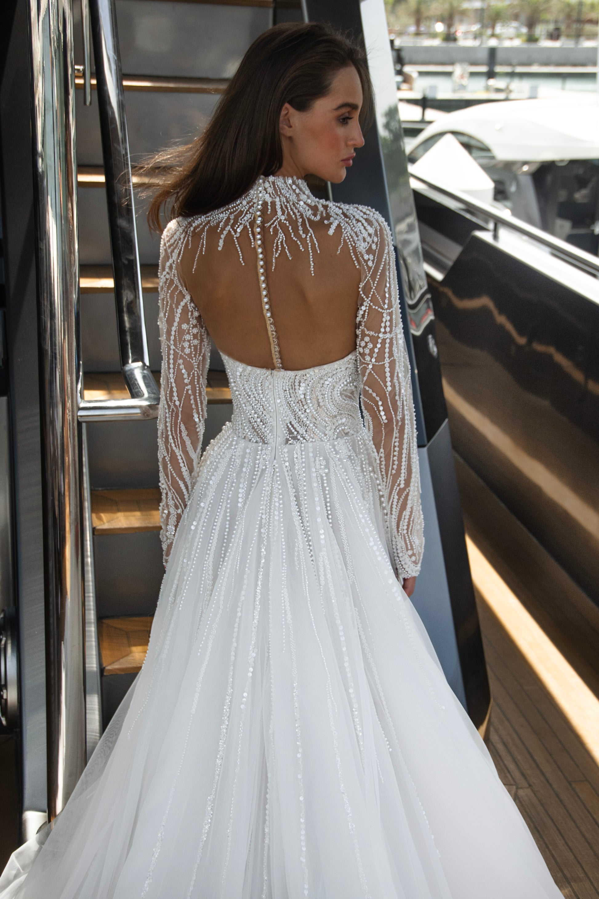 Bride wearing a beaded A-line wedding gown with sweetheart neckline and detachable illusion bolero featuring long sleeves and open back.