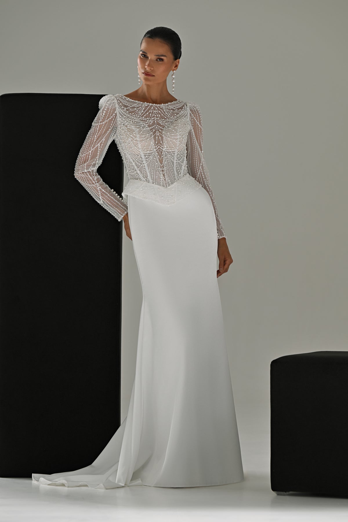 Beaded lace sheath wedding dress with illusion neckline and long sleeves – full-length front view leaning on a black block