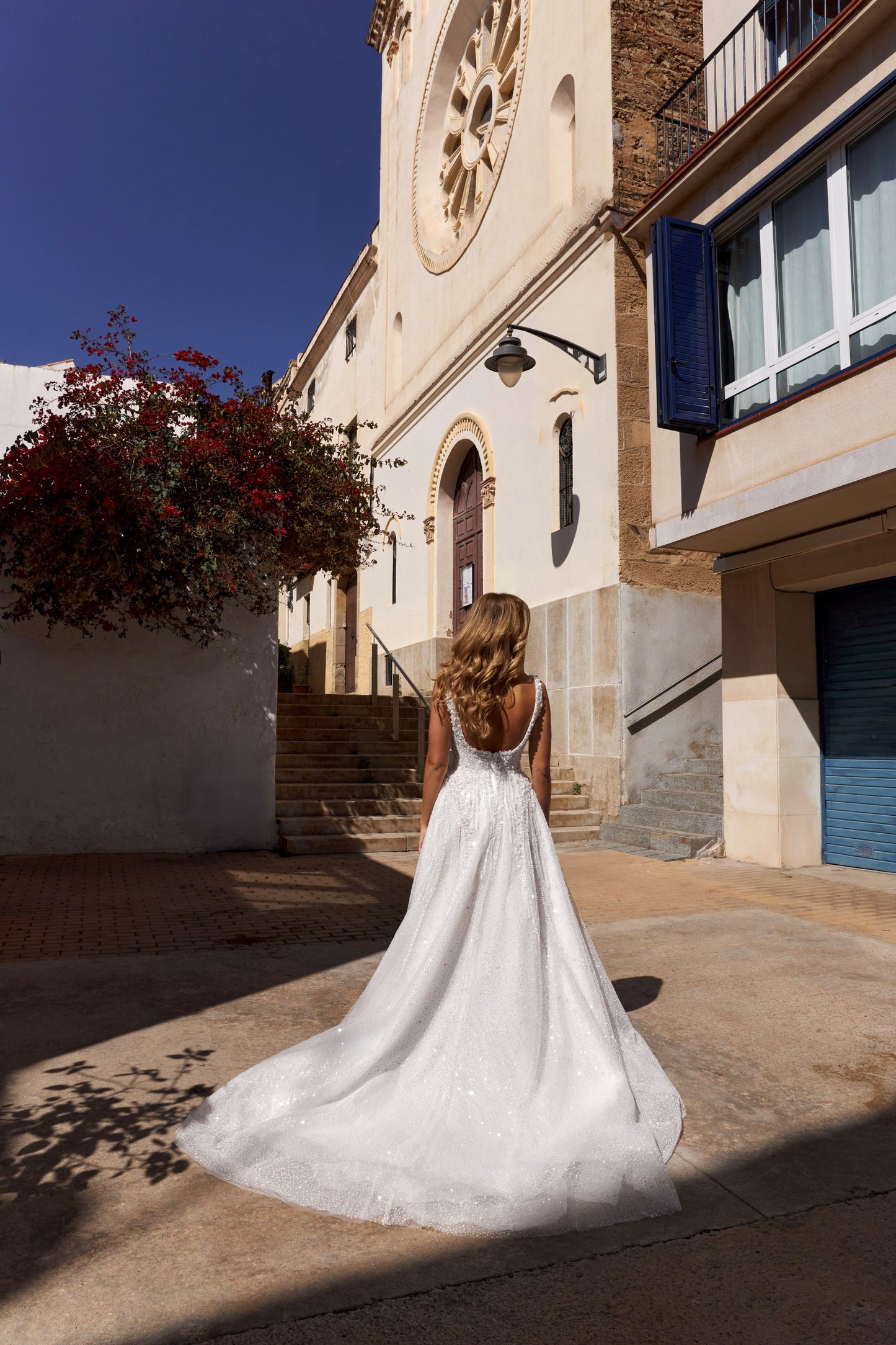 Bride wearing an A-line tulle wedding dress with square neckline, pearl and sequin embroidered lace bodice, glitter tulle skirt, and zip closure.