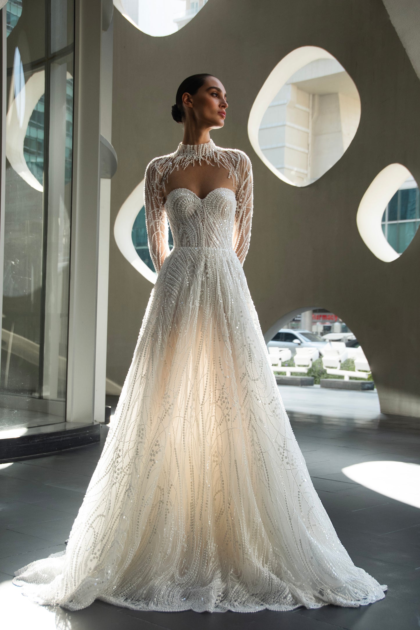 Back view of beaded A-line bridal gown with detachable illusion high-neck bolero, sheer long sleeves, button-back, and chapel train.