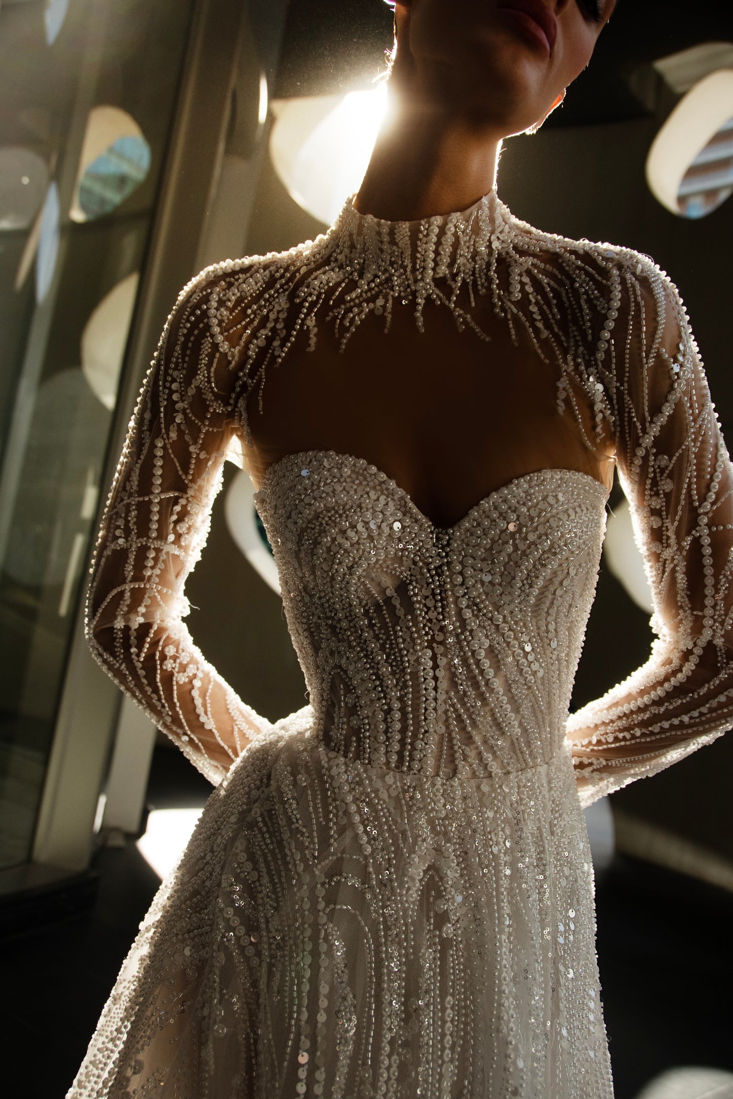 beaded A-line bridal gown with detachable illusion high-neck bolero, sheer long sleeves, button-back, and chapel train.