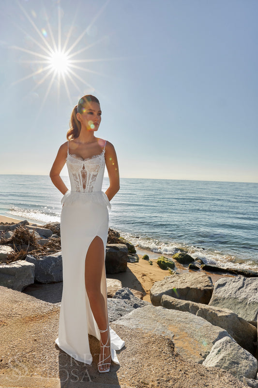 Bride in sleeveless sheath wedding gown with lace bodice, spaghetti straps, slit skirt, zip closure, and sweep train.