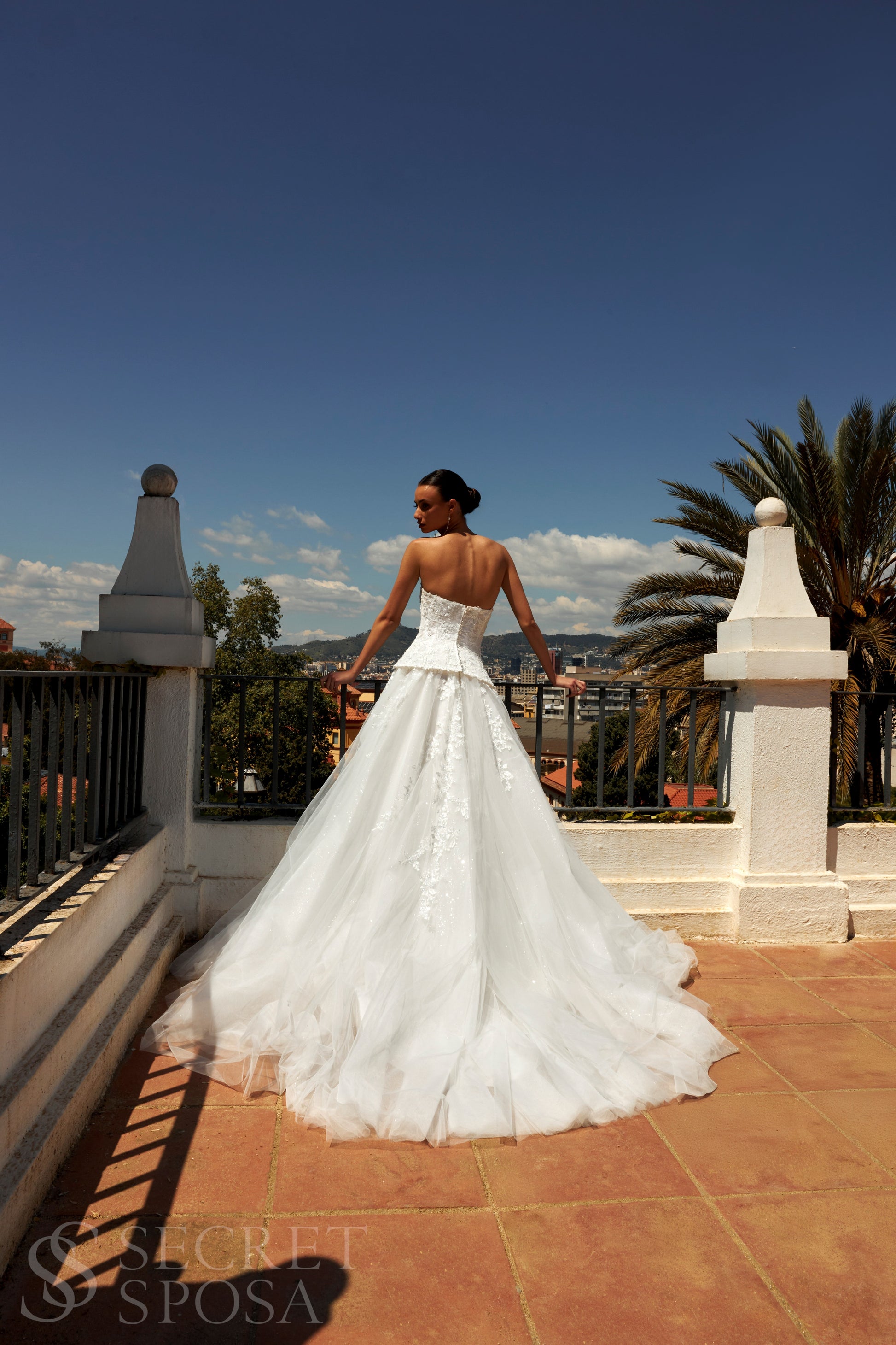 Bride in strapless sweetheart sleeveless A-line wedding gown with sequin lace corset, flowing tulle skirt, and chapel train.