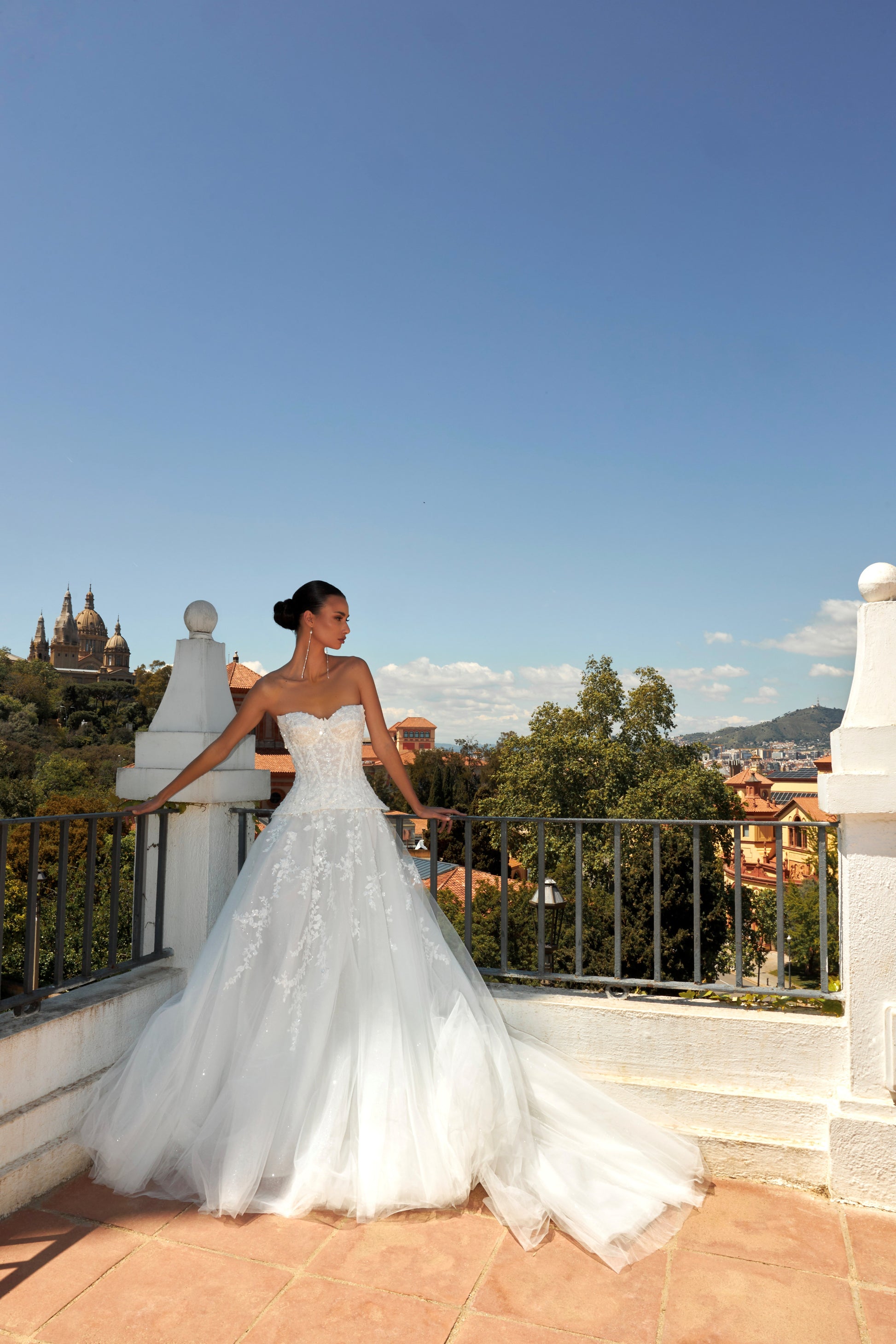 Bride in strapless sweetheart sleeveless A-line wedding gown with sequin lace corset, flowing tulle skirt, and chapel train.