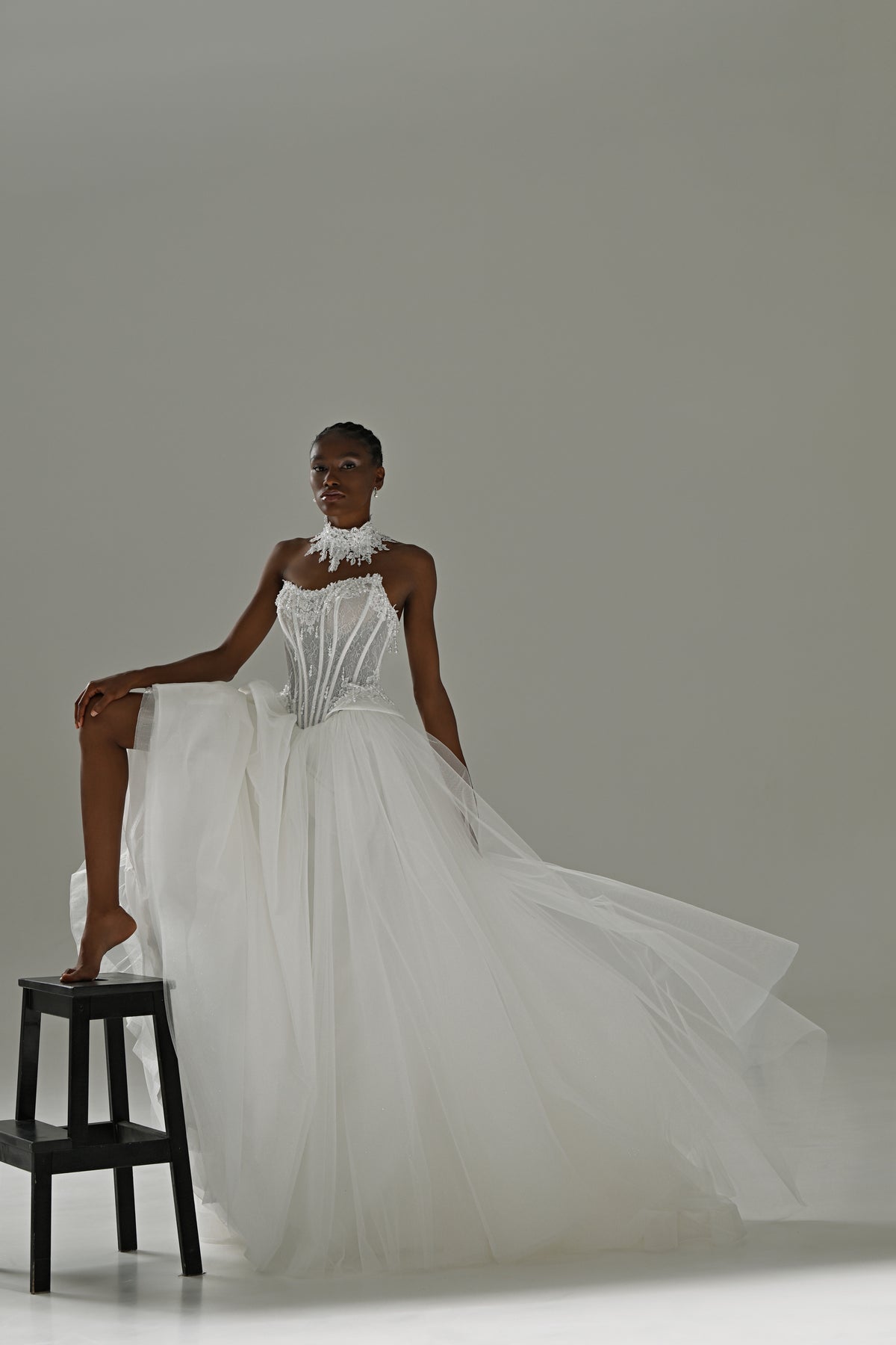 Tulle ball gown wedding dress with strapless lace corset – model with one foot on a stool, tulle skirt spread out